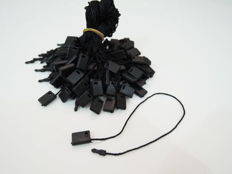 May include: A bulk pack of black string tags with black plastic tips. The tags are tied together and ready to be used for labeling.