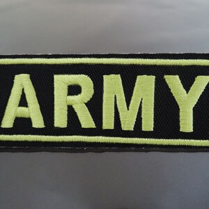 May include: A black embroidered patch with a yellow outline and the word "ARMY" in yellow lettering.