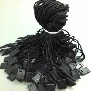 May include: A large pile of black string with small black plastic tags attached to the ends. The string is twisted and bundled together.