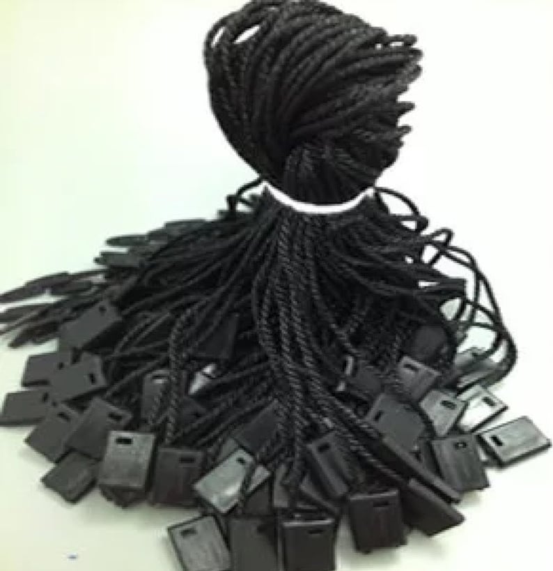 May include: A large pile of black string with small black plastic tags attached to the ends. The string is twisted and bundled together.