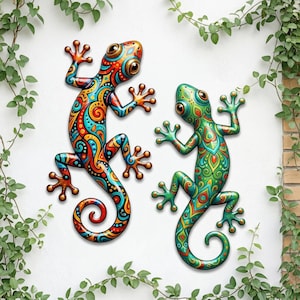 May include: Two wall-mounted lizard sculptures featuring intricate, colorful patterns. The left lizard displays vibrant orange, red, and blue swirls, while the right lizard features shades of green and yellow with detailed, symmetrical leaf-like motifs.
