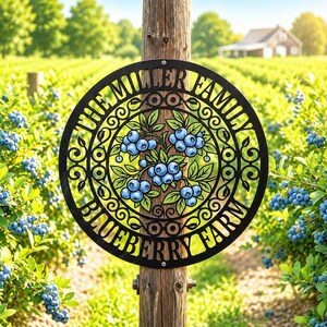 May include: A circular black metal sign featuring a cutout design of blueberry clusters with green leaves. The text "THE MILLER FAMILY" is arched at the top and "BLUEBERRY FARM" is arched at the bottom, mounted on a wooden post.