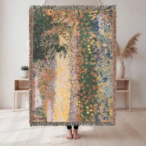 Pode incluir: Uma manta retangular tecida apresentando uma cena de jardim impressionista vibrante com faixas verticais de padrões florais em amarelo, laranja, verde e azul. A manta possui uma borda texturizada com franjas em todos os quatro lados.