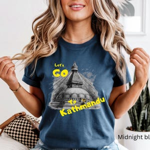 May include: Midnight blue t-shirt with a graphic of a Nepalese stupa and the text "Let's Go to Kathmandu" in yellow. The shirt is a crew neck and has short sleeves.