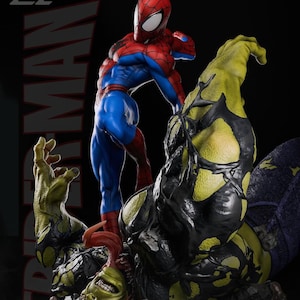 May include: A detailed statue of Spider-Man in a dynamic pose, clad in his signature red and blue suit, standing over a monstrous green and black figure. The statue has intricate detailing and a dramatic composition.