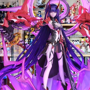 May include: An anime-style figurine of a female character with long purple hair, dressed in a black and white outfit with red details. The figure is set within a purple and red decorative structure, on a crystal-like base.