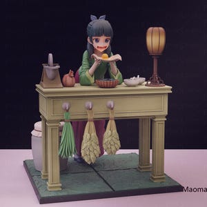 May include: A detailed figurine of a woman in a green and red outfit, holding a small plate with a yellow item. She stands behind a light green table with a lamp, bowls, and hanging bundles. The base is green with a tile pattern.
