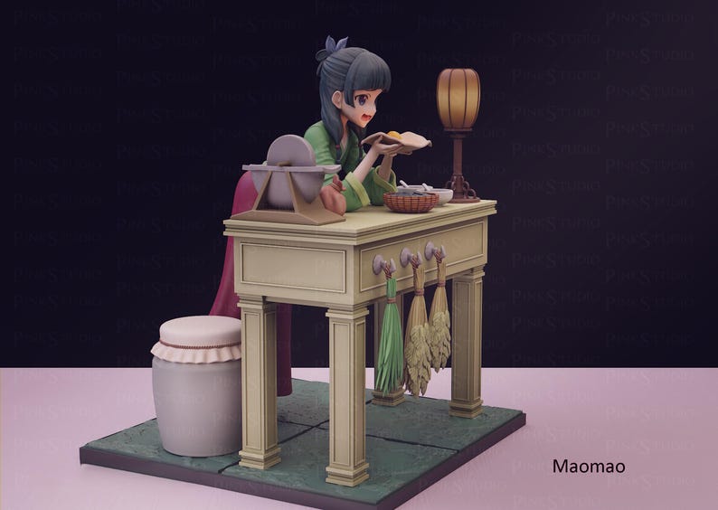May include: A detailed figurine of a woman in a green outfit, seated at a table. The table has a lamp, a basket, and other items. The figurine is on a green base with a pink background. The figurine is labeled "Maomao".