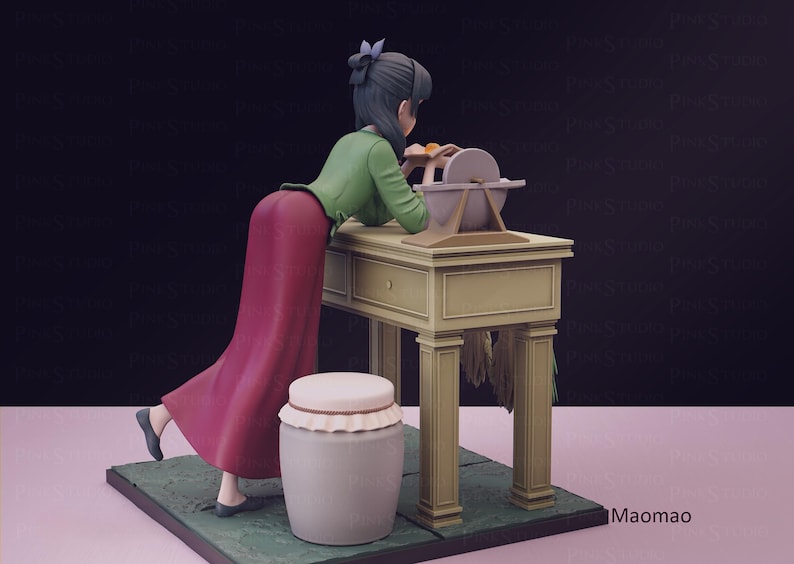 May include: A figurine of a woman in a long red skirt and green jacket, leaning over a table with a grinding wheel. A white jar with a lid sits nearby. The scene is set on a green base.
