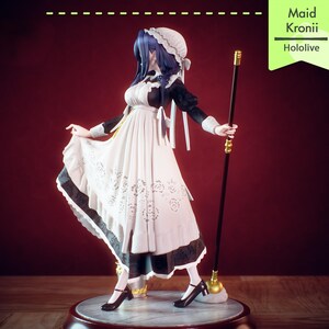 Pu&ograve; includere: Una statuina di Maid Kronii di Hololive, vestita con un abito da cameriera bianco e nero con un grembiule bianco. Tiene in mano un bastone nero con dettagli dorati. La statuina &egrave; su una base rotonda con sfondo rosso scuro.