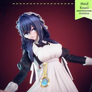 Pu&ograve; includere: Statuetta di un personaggio in abito da cameriera con capelli blu e occhi blu. La statuetta indossa un vestito bianco con maniche nere e un ciondolo dorato. Il testo "Maid Kronii Hololive" &egrave; in un riquadro verde.