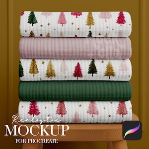 May include: A stack of folded fabric with Christmas tree patterns in red, green, and gold on a white background. The stack includes a solid pink and a solid green fabric. The text "Realistic Mockup for Procreate" is at the bottom.