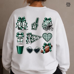 May include: A white crewneck sweatshirt featuring a graphic print on the back. The design includes green cowboy boots, a number one foam finger, a football helmet, a can labeled 215, a Philly pennant, a heart, a green cup, heart sunglasses, and a football.