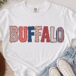 May include: A white short-sleeve t-shirt featuring the word BUFFALO across the chest in large, distressed-edge letters. Each letter displays a different pattern, including red and white gingham, blue with white stars, and red paisley.