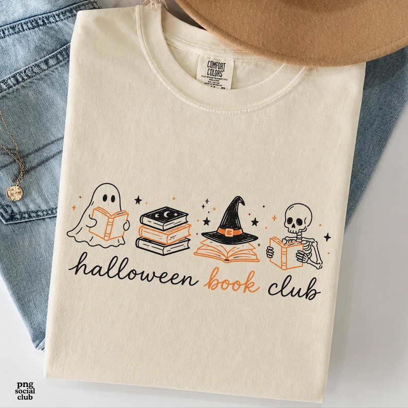Puede incluir: Una camiseta de cuello redondo color crema con un estampado gr&aacute;fico de un fantasma, una pila de libros, un sombrero de bruja sobre un libro abierto y un esqueleto, todos leyendo. El texto bajo las ilustraciones dice "halloween book club".