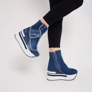 May include: Blue denim wedge sneakers with white soles and a zipper detail. The sneakers have a high-top design with frayed edges and the text "STAR BLUE" on the side. The wedge heel measures approximately 3 inches.
