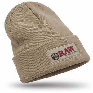 May include: A tan ribbed knit beanie featuring a rectangular patch on the cuff. The patch displays the red text RAW, the phrase THE NATURAL WAY TO ROLL, and a circular logo with the text AUTHENTIC PUREST NATURAL FIBERS.