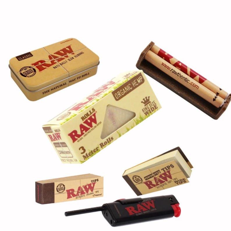 May include: An assortment of RAW brand smoking accessories, including a metal tin, rolling papers, filter tips, a rolling machine, and a lighter. The products feature the RAW logo and branding, with a natural, earthy aesthetic.