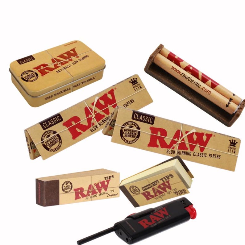 May include: An assortment of RAW brand smoking accessories, including rolling papers, tips, a metal tin, a rolling machine, and a lighter. The products feature the RAW logo in red on a natural brown background.
