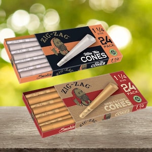 May include: Two boxes of Zig-Zag cones are displayed. One box is black and orange, labeled "Ultra Thin Cones." The other is brown, labeled "Unbleached Cones." Both boxes show the Zig-Zag logo and state "1 1/4 Size" and "24 Pack."