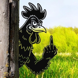 Könnte beinhalten: Ein schwarzes Metall-Gartendekorationsobjekt in Form eines Hahns mit gelbem Schnabel und Kamm, der den Mittelfinger zeigt. Der Hahn befindet sich neben einem verwitterten Holzpfosten, mit einer grünen Wiese und blauem Himmel im Hintergrund.