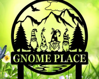 May include: Black metal garden stake with a circular design depicting a mountain and tree silhouette. The words "GNOME PLACE" are displayed below five gnome figures. A butterfly and flowers are in the background.
