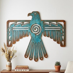 May include: A large, flat metal wall art piece shaped like a stylized bird with outstretched wings. The surface features a weathered, oxidized turquoise patina with exposed rusted brown edges and a central spiral cutout design on the bird's chest.