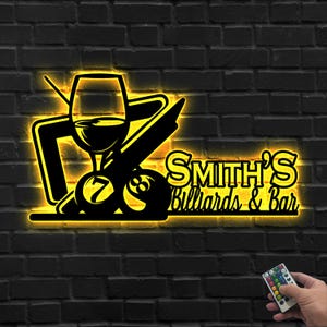 May include: A black metal sign with a yellow neon outline, featuring a wine glass, pool balls, and a cue stick. The sign reads "Smith's Billiards & Bar" in a stylized font. The sign is mounted on a dark brick wall.
