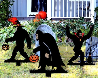 May include: Three black metal Halloween yard decorations depicting gorilla figures. One wears a witch's hat and carries a jack-o'-lantern. Another wears a cape and carries a jack-o'-lantern. The third has a vampire cape and raises its arms.