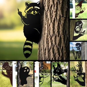 Pode incluir: Decoração de jardim em metal preto com um guaxinim a fazer um gesto obsceno, espreitando por trás de uma árvore. Outros desenhos incluem um gnomo, gorila, esqueleto, cão, fantasma, buldogue, esquilo e veado, todos com o mesmo gesto.