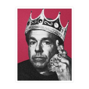 May include: A sticker featuring a black and white image of a man wearing a silver crown and multiple rings. The background is a solid red color. The man is looking directly at the viewer.