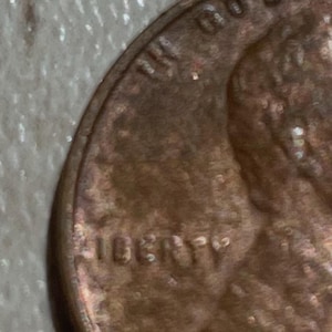 Puede incluir: Primer plano de una moneda de cobre. La palabra "LIBERTY" es visible, junto con otro texto parcialmente visible. La moneda tiene un aspecto desgastado.