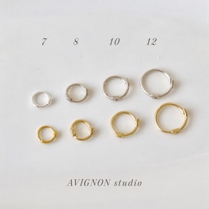 May include: A selection of small hoop earrings in silver and gold, arranged in rows. Sizes 7, 8, 10, and 12 are indicated above the earrings. The text "AVIGNON studio" is printed below the earrings.