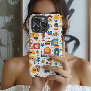 May include: A white phone case featuring a colorful pattern of cartoon characters and shapes. The design includes the text "tall." and "TOY STORY". The case has a glossy finish and is designed for a smartphone.
