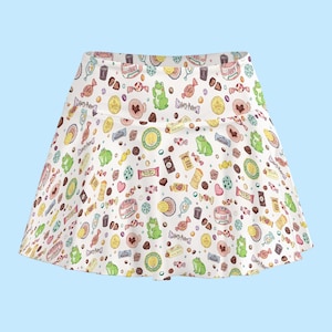 May include: White skater skirt with a colorful pattern of candies, chocolate frogs, and other sweets. The skirt features a repeating design with the text "Harry Potter" on some of the elements. The skirt has a wide waistband and a flared silhouette.