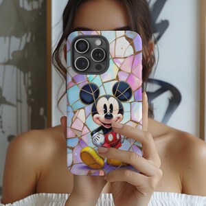 May include: A smartphone case featuring a colorful mosaic design with a cartoon image of Mickey Mouse. The case has a black camera module and a mosaic pattern in shades of pink, purple, and blue, with gold accents.