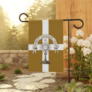May include: A garden flag with a gold background and a white cross design. The flag features a detailed illustration of a chalice with a sunburst and the text "ADVENIAT REGNUM TUUM" on a banner. The flag is displayed on a black metal stand.