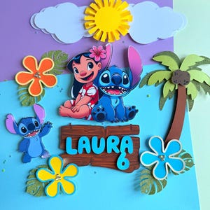 Op de afbeelding: Een kleurrijke handgemaakte kaart met de personages Lilo en Stitch, een gele zon, witte wolken en tropische bloemen. De naam "LAURA" en het nummer "6" staan op een houten bord. De achtergrond is een mix van paars, blauw en groen.