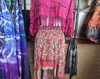 Pink snap up blouse cropped and fringed paired with floral and multi-patterned asymmetrical skirt.
