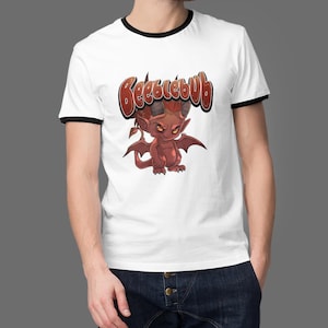 May include: White t-shirt with black trim on the collar and sleeves. The shirt features a cartoon illustration of a red devil with the word "Beelzebub" in brown text above the devil.