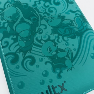 May include: Teal card binder with embossed cartoon turtle-like creatures and water effects. The word "vaultx" is printed in black at the bottom. The binder has white stitching along the edges.