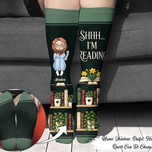 May include: A pair of dark green crew socks featuring a cartoon illustration of a person with glasses holding a mug, the text SHHH... I'M READING, a book with yellow flowers, and shelves filled with various books and potted plants on the lower sections.