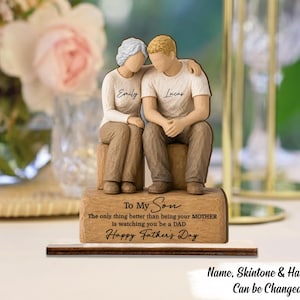 Peut inclure: Figurine en bois d'une mère et de son fils, le bras du fils autour de la mère. La mère porte un pull blanc avec "Emily". Le fils porte un t-shirt blanc avec "Lucas". La base indique "To My Son" et "Happy Father's Day".