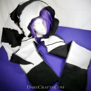 May include: Black and white hooded scarf with a contrasting white trim. The scarf is made of fleece and has a checkered pattern.