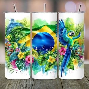 May include: Three white insulated tumblers with a Brazilian theme. Each tumbler features a vibrant design of the Brazilian flag, tropical foliage, and a colourful macaw parrot. The tumblers have silver straws.