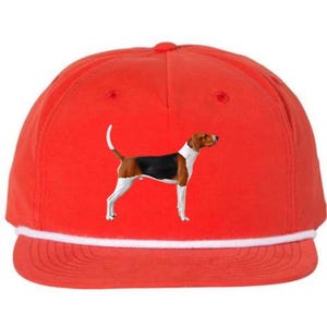 May include: A red baseball cap with a white rope detail and a graphic of a dog. The dog is a tricolor hound with a black, brown, and white coat. The hat has a curved brim.