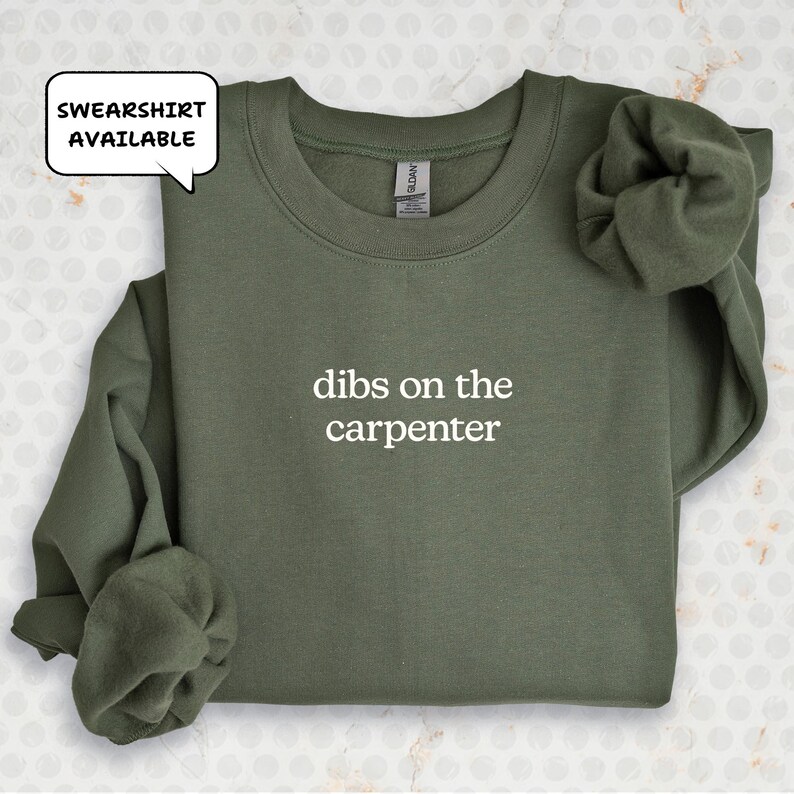 A green sweatshirt with the text "dibs on the carpenter" printed on it.