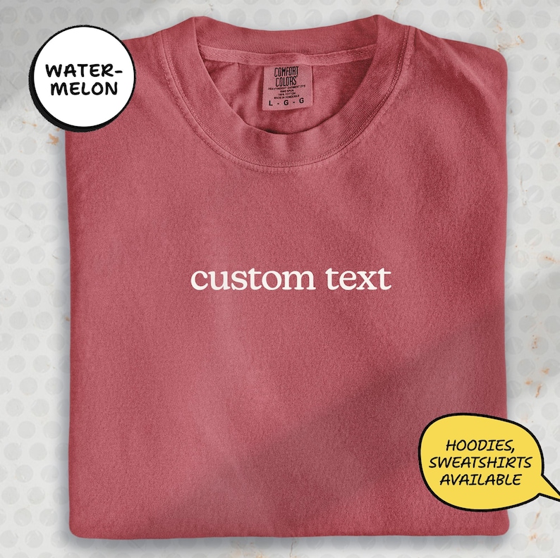 A red t-shirt with the text "watermelon custom text" printed on it, along with a label indicating it is a "Comfort" brand. The t-shirt is folded and displayed on a white background, with a speech bubble indicating that hoodies and sweatshirts are available.