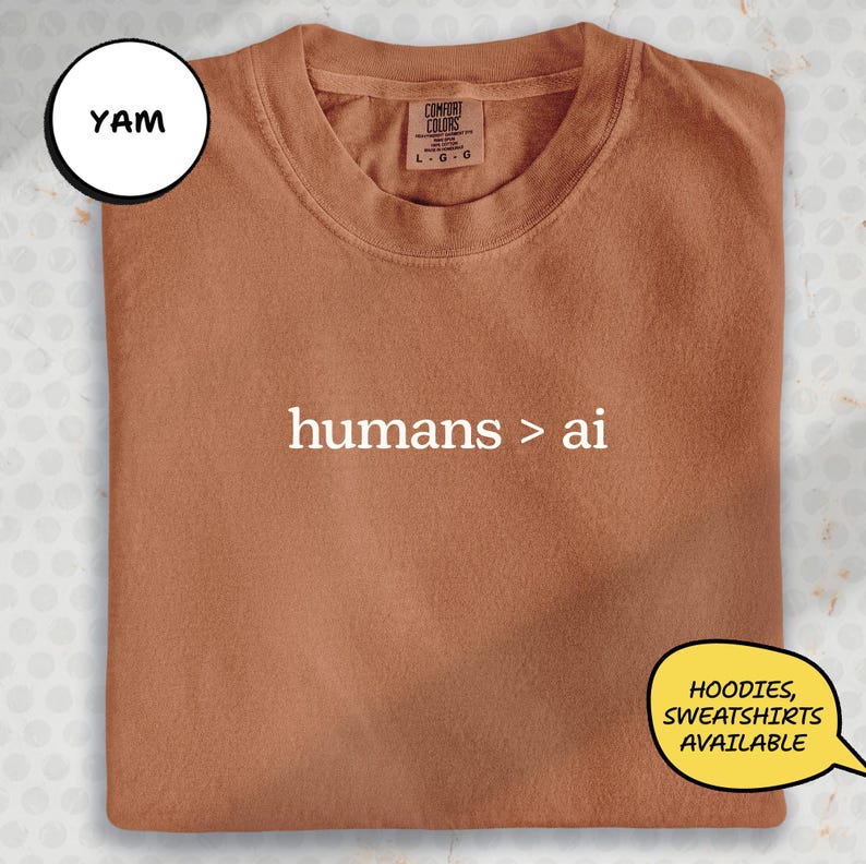 a brown t-shirt with the text "hums > ai" printed on it.