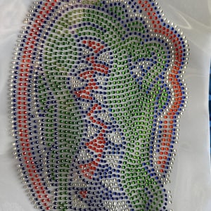 May include: An oval-shaped iron-on rhinestone transfer patch featuring a stylized alligator head design. The pattern is composed of small, circular, faceted rhinestones in vibrant shades of green, blue, red, and clear, arranged on a white backing.